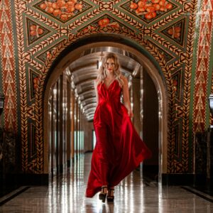 A woman in a stunning red dress walking through an ornate hallway in Detroit.