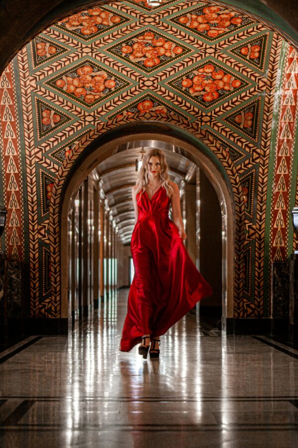 A woman in a stunning red dress walking through an ornate hallway in Detroit.